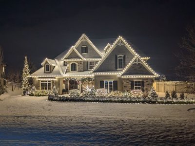 Clear Choice: A large two-story home adorned with white Christmas lights, surrounded by a snowy landscape at night, reflecting elegant interior design.
