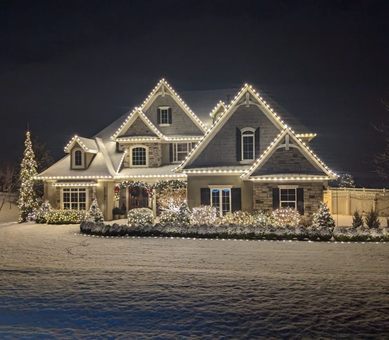 Clear Choice: A large two-story home adorned with white Christmas lights, surrounded by a snowy landscape at night, reflecting elegant interior design.