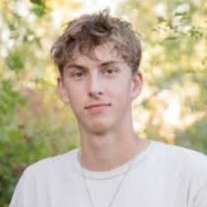 Clear Choice: Young man wearing a white shirt stands outdoors with trees in the background.