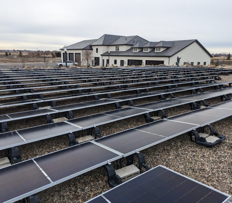Clear Choice: Rows of solar panels in front of a large modern house with a grey roof, located in Boise Valley under a cloudy sky.